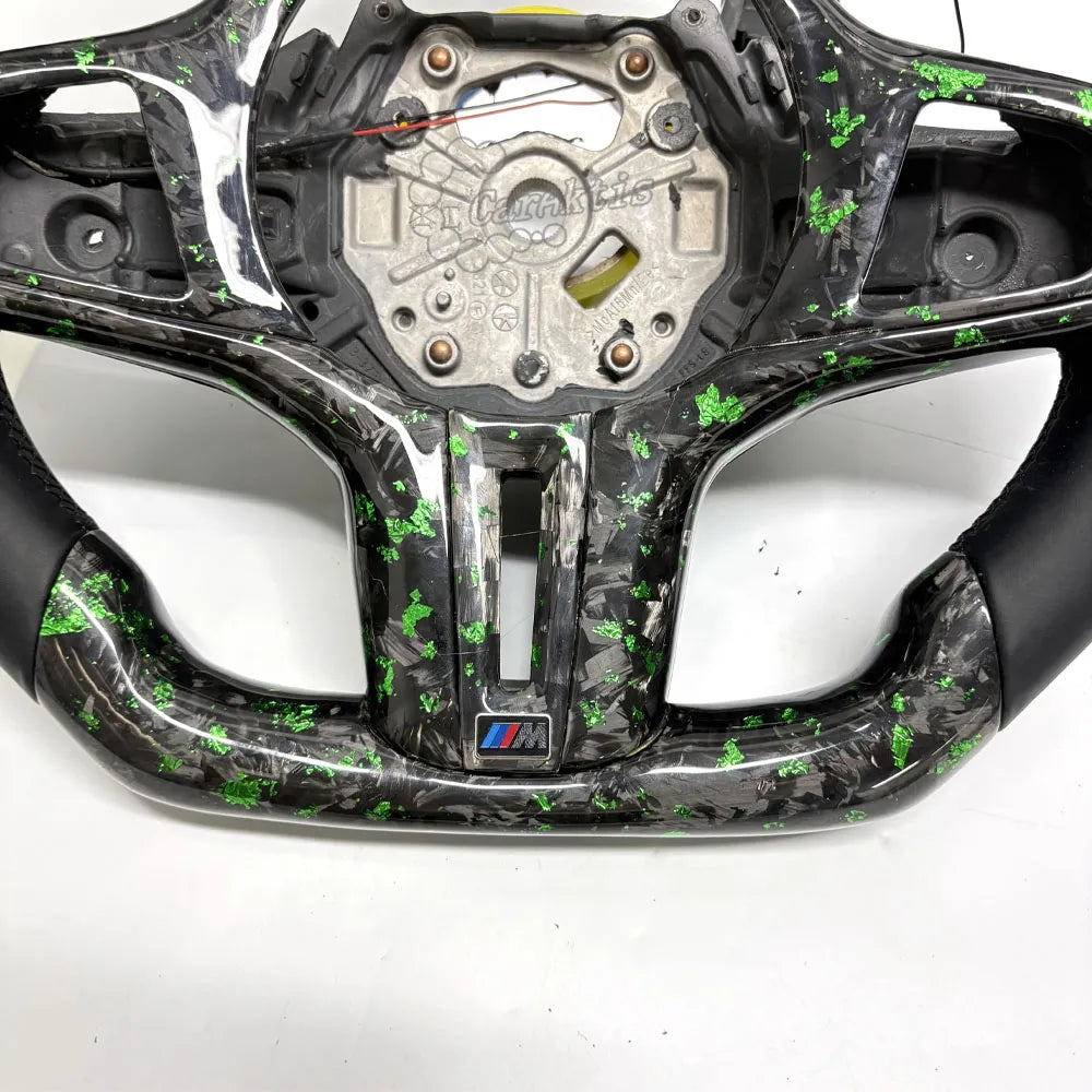 This custom BMW steering wheel is crafted from premium forged carbon fiber, showcasing a unique, close-up marble-like texture.
