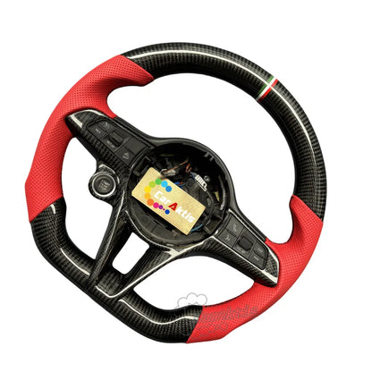 A custom steering wheel designed specifically for Alfa Romeo, featuring glossy carbon fiber at the top and bottom, a tri-color centering stripe in the center, and perforated leather grips with red accents on both sides.