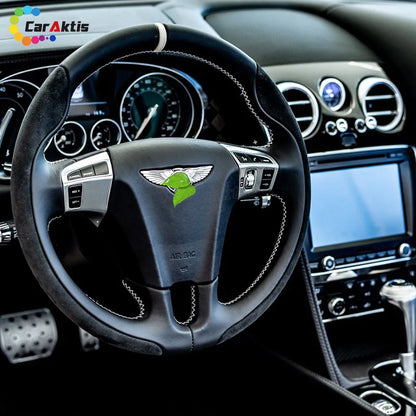 Interior view of a Bentley Continental GT with a custom Alcantara and carbon fiber steering wheel installed in the luxury cabin.