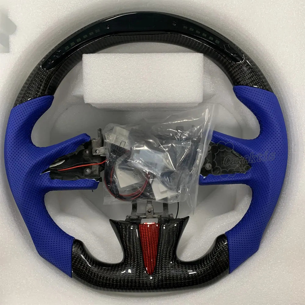 A custom carbon fiber steering wheel designed specifically for the Infiniti Q50 and Q60, featuring a glossy carbon fiber finish, blue perforated leather wrapping on the sides, and a flat-bottomed D-shape design.
