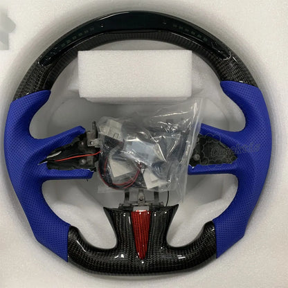 A custom carbon fiber steering wheel designed specifically for the Infiniti Q50 and Q60, featuring a glossy carbon fiber finish, blue perforated leather wrapping on the sides, and a flat-bottomed D-shape design.