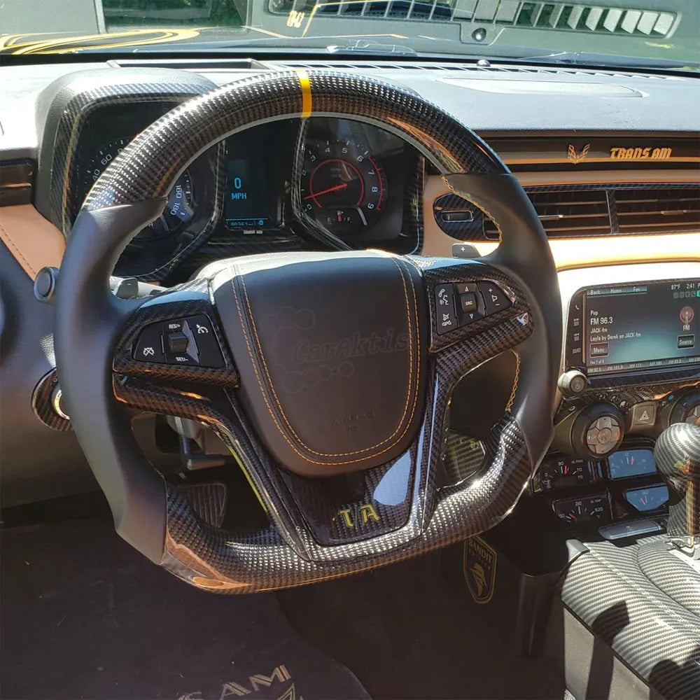 Installed view of a custom gloss carbon fiber steering wheel with red and yellow center accents in a 2012-2015 Chevy Camaro interior, showing a perfect OEM fit.