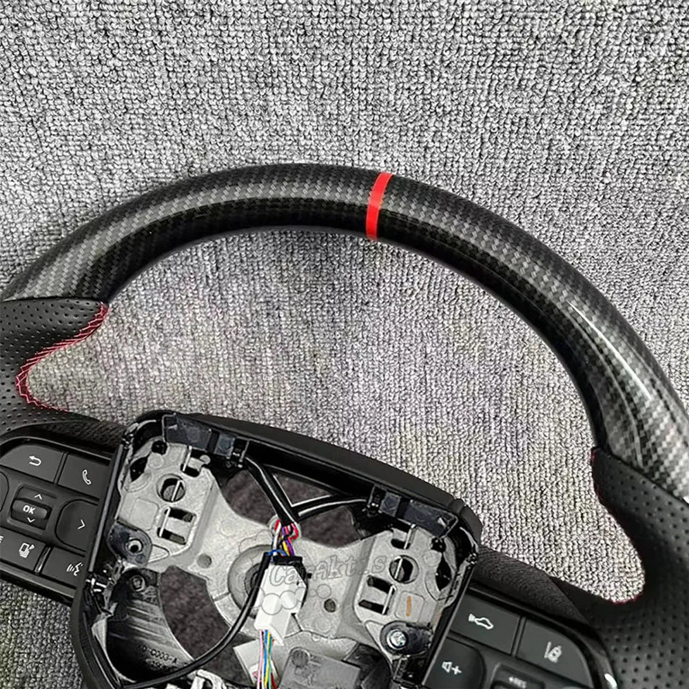 Close-up of the racing red center marker on a glossy carbon fiber steering wheel for Toyota Hilux, showcasing the premium weave and red.