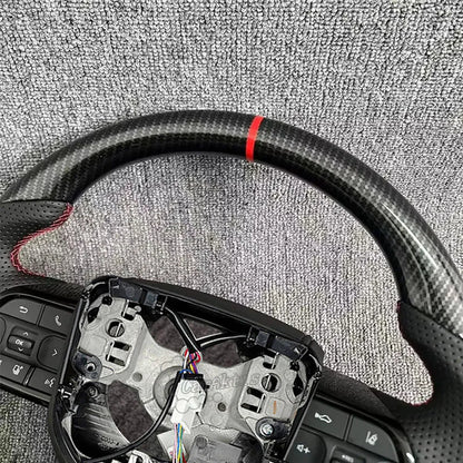 Close-up of the racing red center marker on a glossy carbon fiber steering wheel for Toyota Hilux, showcasing the premium weave and red.
