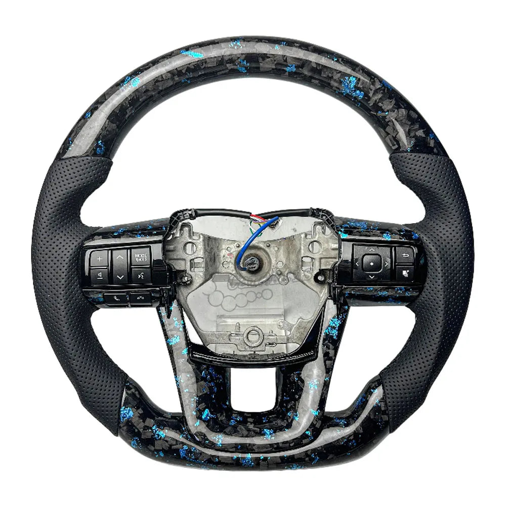 Close-up of the unique marble-like forged carbon fiber finish on a custom Toyota Hilux steering wheel.