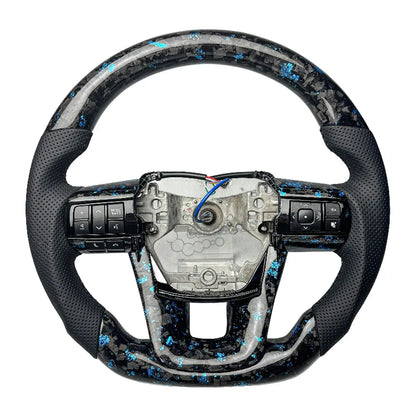 Close-up of the unique marble-like forged carbon fiber finish on a custom Toyota Hilux steering wheel.