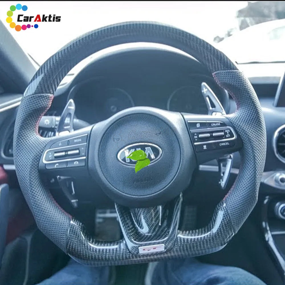 Installed view of a custom glossy carbon fiber steering wheel with black perforated leather and red stitching for Kia Stinger 2017-2024.