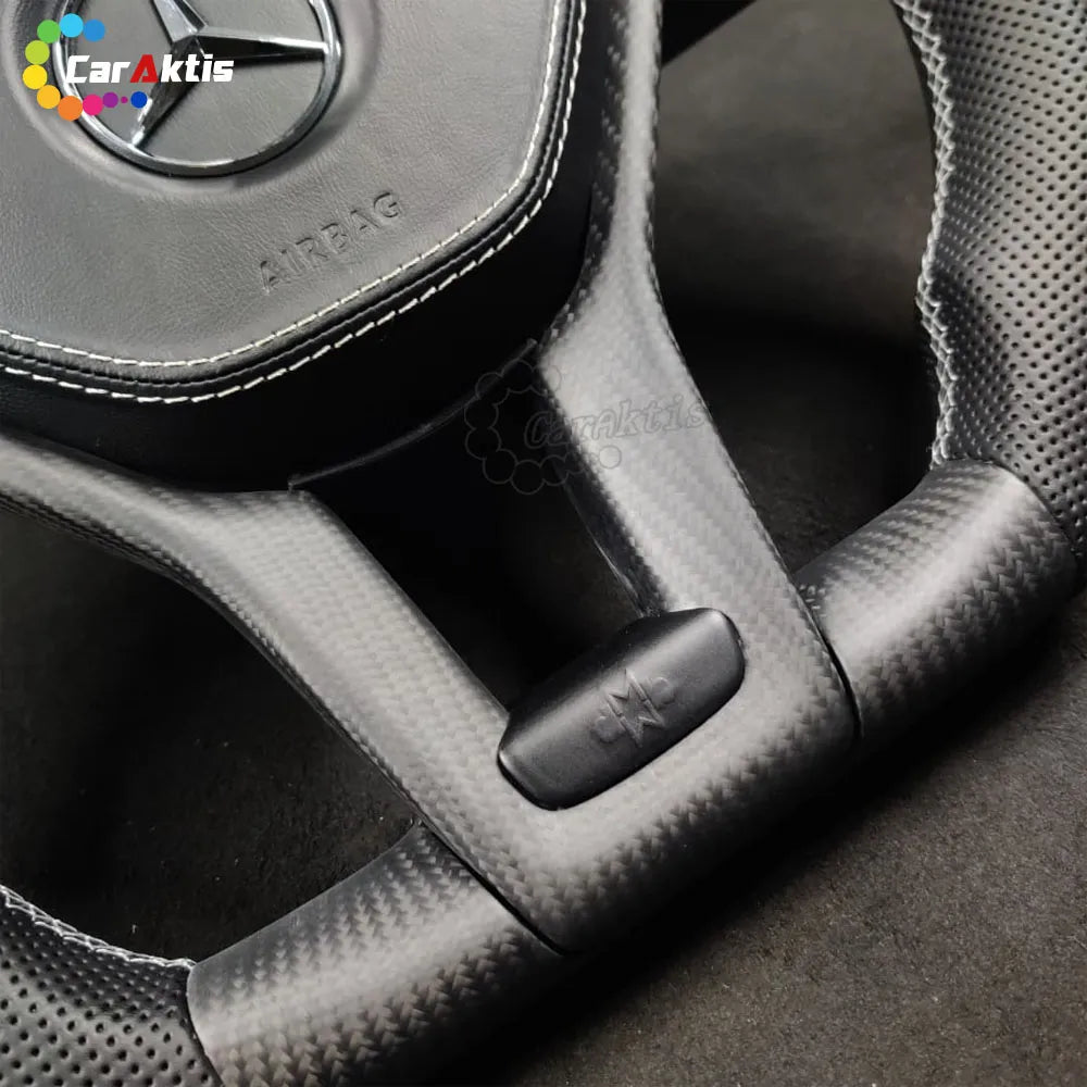 Close-up of matte carbon fiber finish and white stitching on a custom Mercedes W204 steering wheel.
