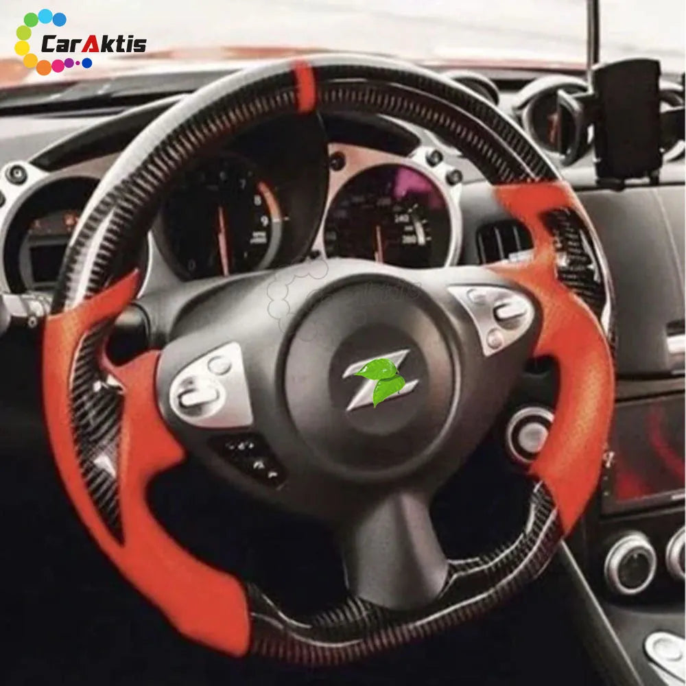 Custom Nissan 370Z steering wheel featuring vibrant orange leather grips and gloss carbon fiber installed in cockpit.
