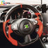 Custom Nissan 370Z steering wheel featuring vibrant orange leather grips and gloss carbon fiber installed in cockpit.