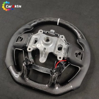 Rear view of a custom Ram steering wheel showing the OEM core structure, carbon fiber finish, and perforated leather stitching detail.
