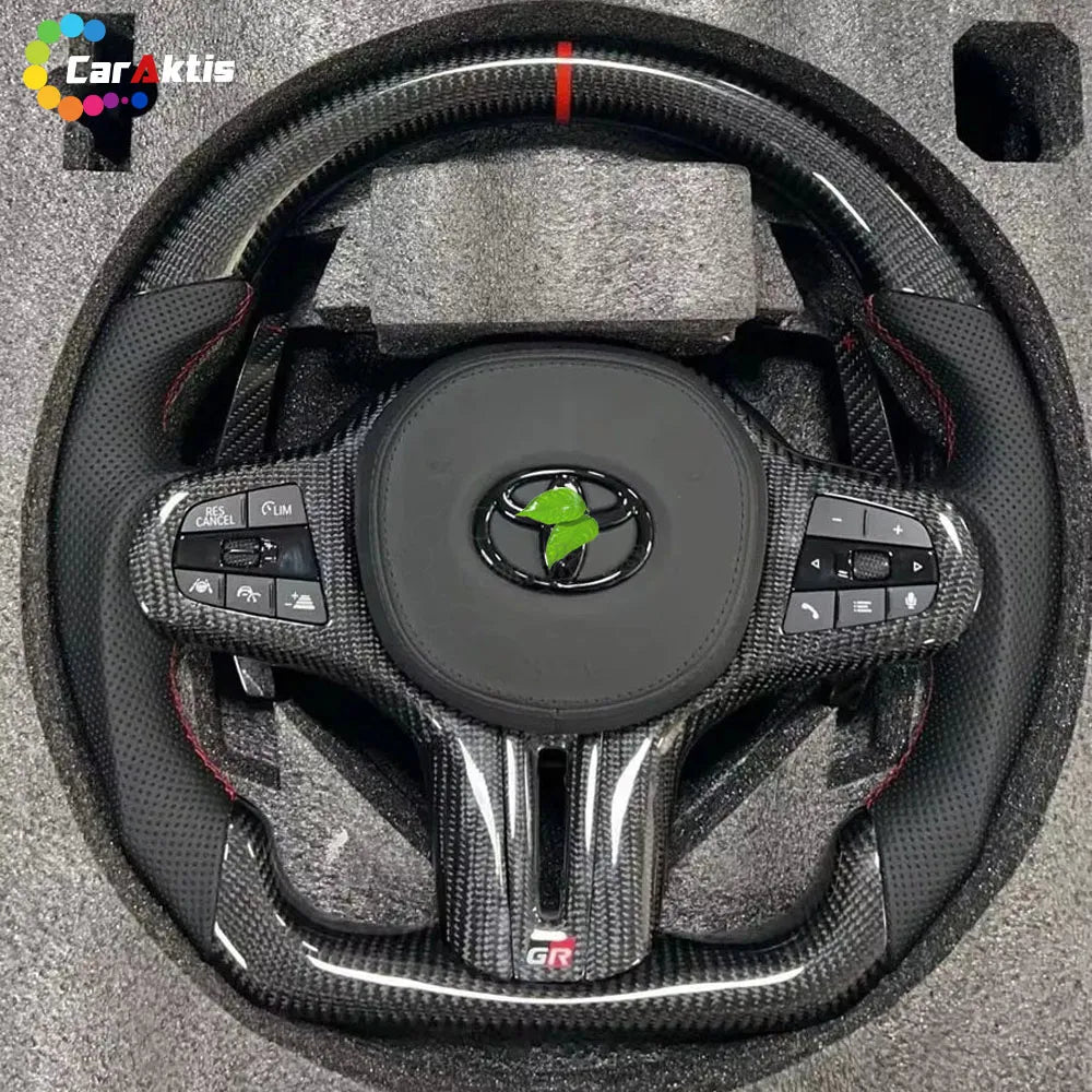 Upgraded carbon fiber steering wheel installed in a Toyota GR Supra A90 cockpit, showing a luxury racing interior look.