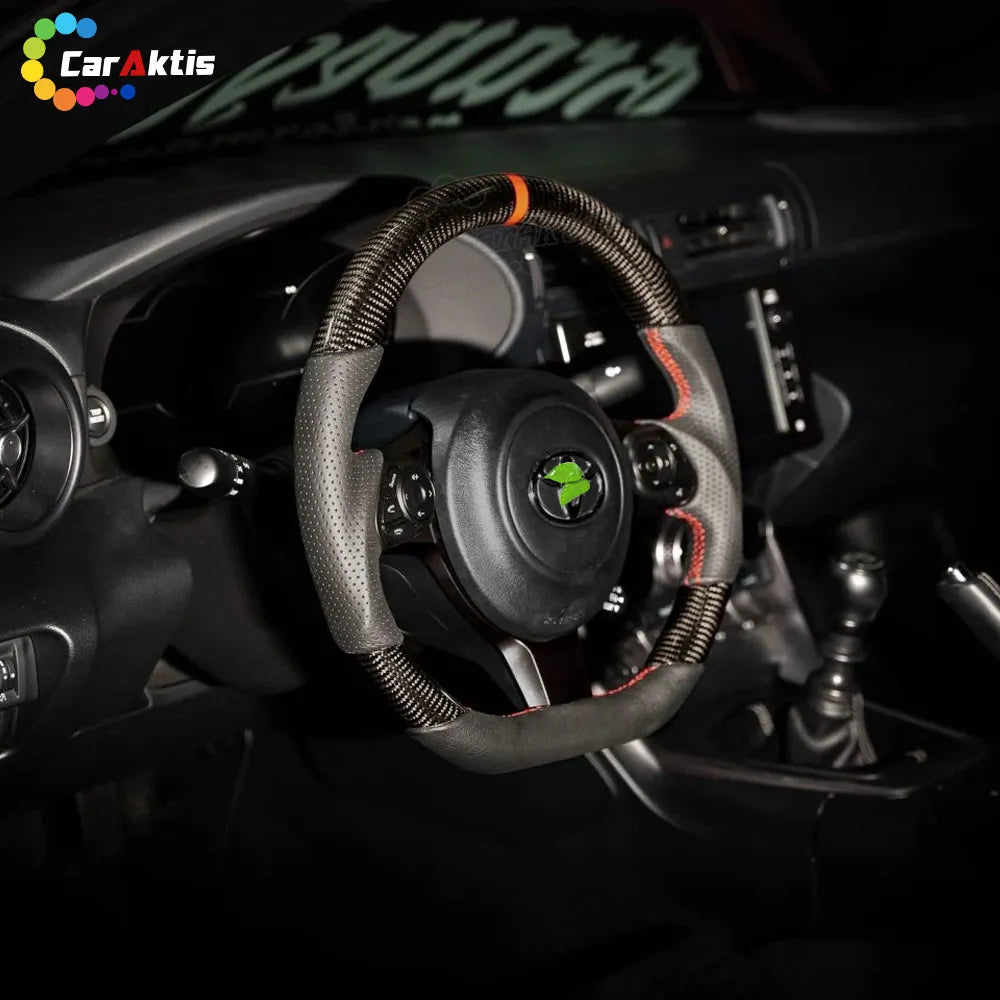 Toyota GR86 interior featuring a custom carbon fiber steering wheel with red stitching.