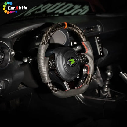 Toyota GR86 interior featuring a custom carbon fiber steering wheel with red stitching.