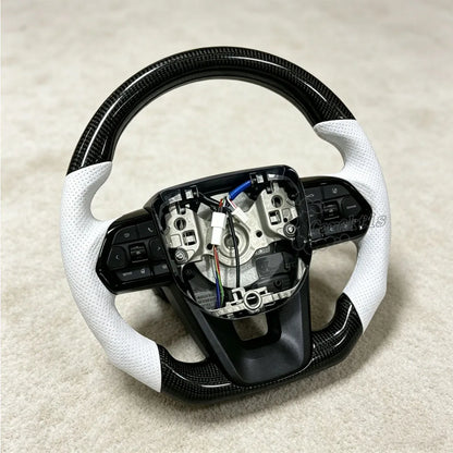 Glossy carbon fiber steering wheel for Toyota Hilux featuring handcrafted white perforated leather grips for enhanced comfort and luxury aesthetics.